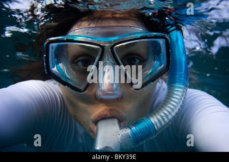 Jeune femme regarde en direction de l'appareil photo à travers un masque tout en snorkling à Maui, Hawaii. Banque D'Images