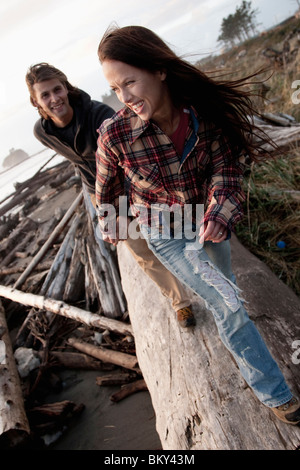 Un jeune couple sourire tout en marchant le long d'une plage. Banque D'Images