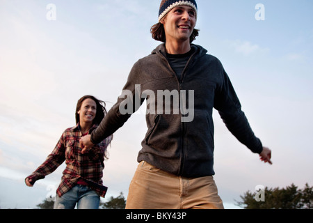 Un jeune couple sourire tout en marchant le long d'une plage. Banque D'Images