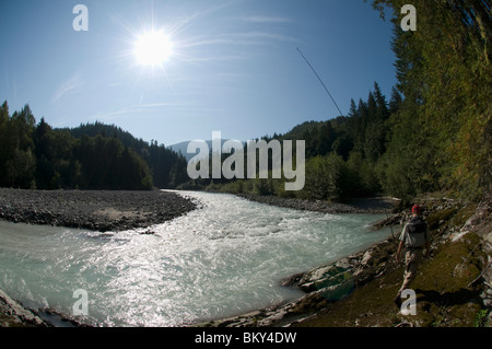 Un homme habillé en waders promenades le long de la rivière avec sa canne à pêche de mouche La pêche de mouche alors que, à Squamish, en Colombie-Britannique. Banque D'Images