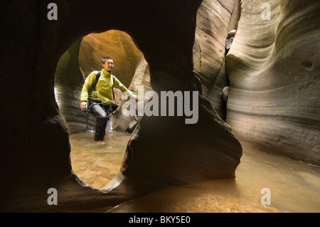 Un homme asiatique le canyoning à travers un canyon aquatique dans la région de Zion National Park, Springdale, Utah. Banque D'Images