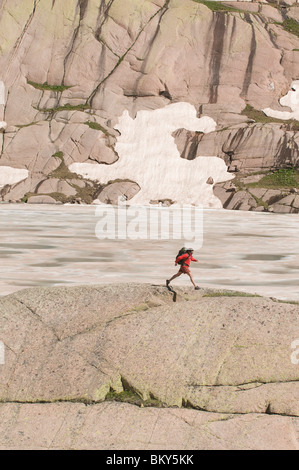 Une femme sur un saut backpacker gap dans les roches lors d'une randonnée, San Juan National Forest, Colorado. Banque D'Images