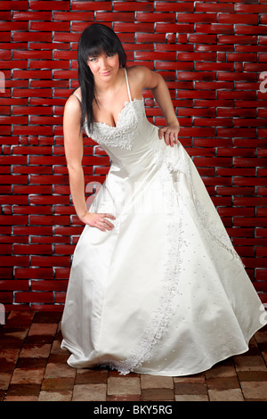 Portrait d'une jeune mariée robe de mariage en standing in front of brick wall Banque D'Images