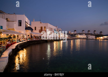 Afficher le long de banque avec restaurants et bars dans la soirée, windmilles en arrière-plan, la Petite Venise, Mykonos-Town, Mykonos, Grèce Banque D'Images