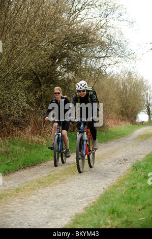 Deux jeunes femmes à vélo sur le sentier, près de l'Ystwyth Tregaron CVeredigion Wales UK Banque D'Images