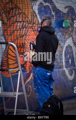 Un graffiti artiste utilise un aérosol de peinture pour créer un morceau à Toronto Banque D'Images