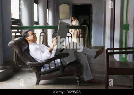 L'homme de lire le journal dans le balcon Banque D'Images