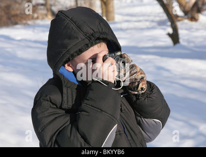 Beau preteen boy taking photos avec un point numérique et appareil photo à l'extérieur en hiver Banque D'Images