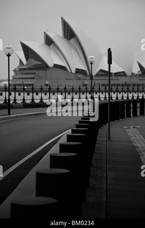 Sydney Opera House à partir de l'autre côté du port, sous le pont, dans une rue avec lampadaires et bornes d'au premier plan Banque D'Images