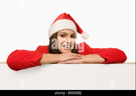 Femme en costume Santa penchées sur un tableau blanc et d'smiling Banque D'Images