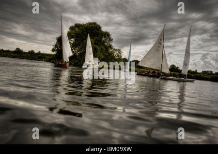 Un petit groupe de bateaux à voile à la préparation pour une course sur les Norfolk Broads, Angleterre Banque D'Images