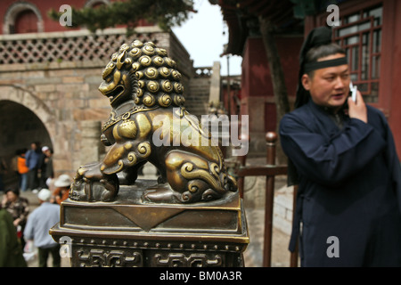 Moine taoïste sur téléphone mobile, gardien, Chien Lion Chinois Foo, Temple Cloud Azure, Tai Shan, province de Shandong, Taishan, Mont Tai Banque D'Images