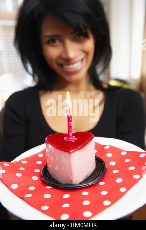 Femme tenant un gâteau en forme de coeur Banque D'Images