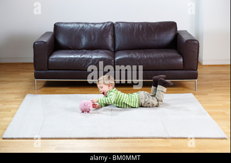 Young boy putting coins in piggy-bank Banque D'Images