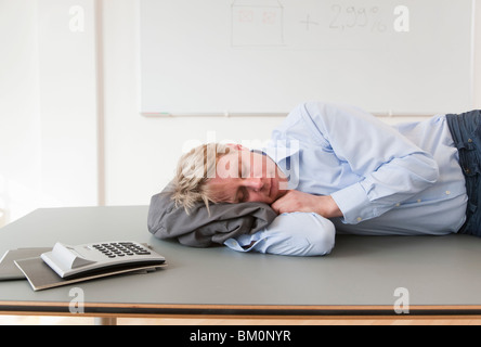 Businessman sleeping on conference table Banque D'Images