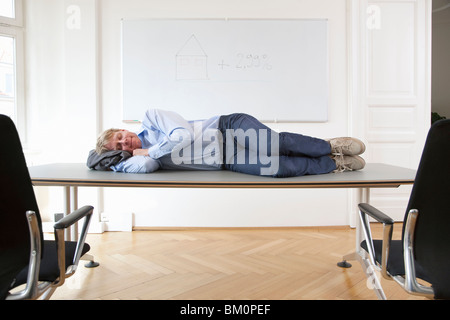 Businessman sleeping on conference table Banque D'Images