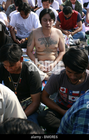 Un homme dans la prière au cours de Wai Kru Journée à Wat Phra Bang, un temple bouddhiste en Thaïlande où les moines dévots de tatouage. Banque D'Images