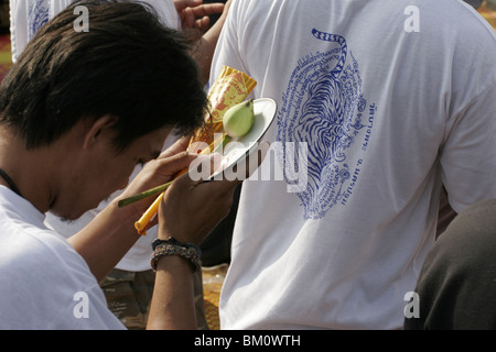 Un homme dans la prière au cours de Wai Kru Journée à Wat Phra Bang, un temple bouddhiste en Thaïlande où les moines dévots de tatouage. Banque D'Images