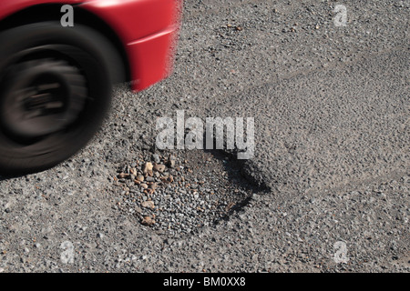 Une voiture passe un pot trou dans une route de banlieue à Hounslow, Middx, UK. Mai 2010 Banque D'Images