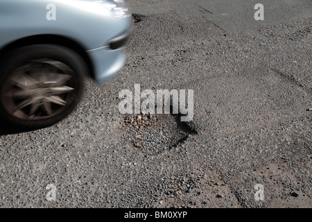 Une voiture passe un pot trou dans une route de banlieue à Hounslow, Middx, UK. Mai 2010 Banque D'Images