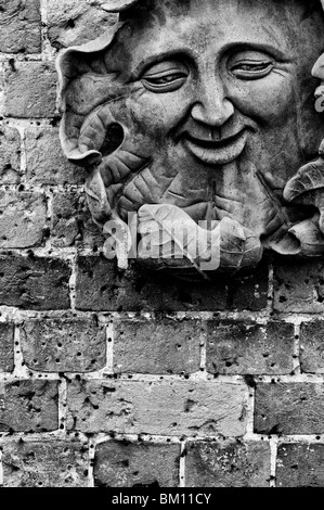 Un homme vert sculpté plaque sur un mur de jardin. Monochrome Banque D'Images