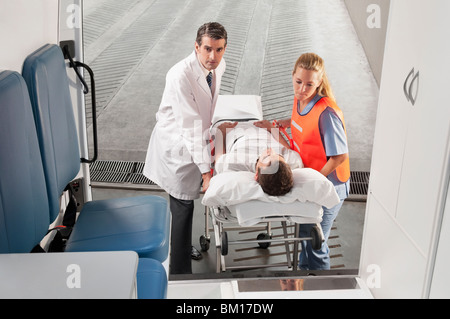 Le personnel paramédical à la tête d'un patient sur une civière dans une ambulance Banque D'Images