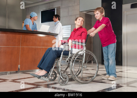 Femme assise dans un fauteuil roulant poussé par son fils Banque D'Images