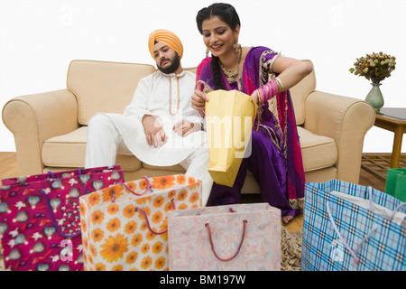 L'homme se reposant sur un divan et la femme contrôle shopping bags Banque D'Images