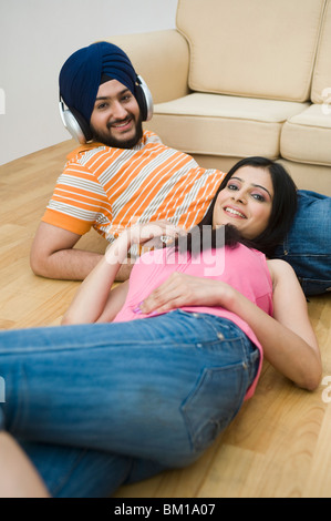 Couple allongé sur le sol et l'homme écoute de la musique Banque D'Images