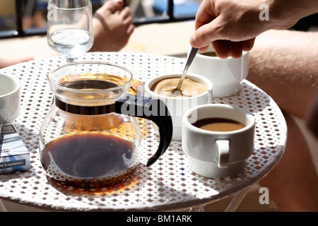 Du café et du lait est versé dans des tasses en vacances à Puerto Pollença appartement près de la plage. Banque D'Images