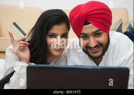 Couple Sikh d'une carte de crédit et de travail sur un ordinateur portable Banque D'Images