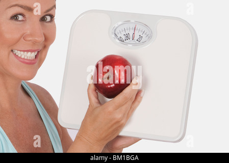 Femme tenant une balance de salle de bains et d'un apple and smiling Banque D'Images