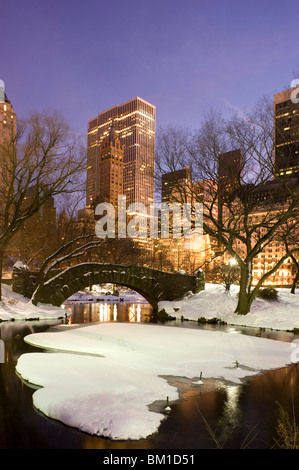 Une vue de l'Gapstow Bridge dans Central Park et les toits de la ville au crépuscule après une tempête de neige, New York City, New York State, USA Banque D'Images