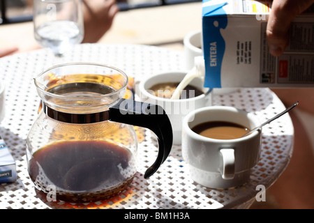 Du café et du lait est versé dans des tasses en vacances à Puerto Pollença appartement près de la plage. Banque D'Images