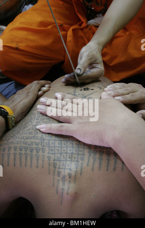 Un homme est tatoué pendant Wai Kru Journée à Wat Phra Bang, un temple bouddhiste en Thaïlande où les moines dévots de tatouage. Banque D'Images
