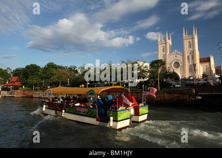 Un bateau de tourisme passe St Francis Xavier église sur la rivière Malacca Malacca ou historique de Melaka, Malaisie. Banque D'Images