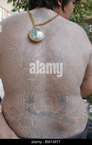 Un jeune homme, montre son tatouage au cours de Wai Kru Journée à Wat Phra Bang, un temple thaïlandais où les moines leur tatouage dévots. Banque D'Images