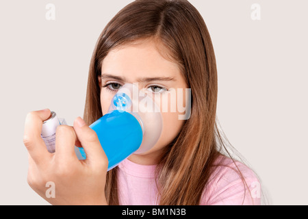 Fille à l'aide d'un inhalateur d'asthme relié avec l'entretoise Banque D'Images