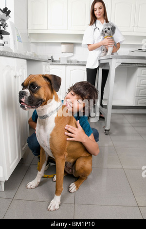 Boy hugging un chien avec un vétérinaire dans l'arrière-plan Banque D'Images