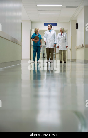 Les médecins et une infirmière marche dans un couloir de l'hôpital Banque D'Images