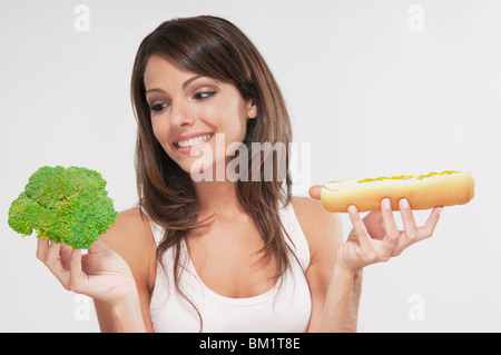 Femme de choisir entre le brocoli et un hot-dog Banque D'Images