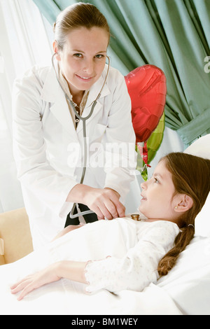 Jeune fille sur un lit d'hôpital en cours d'examen par une femme médecin Banque D'Images