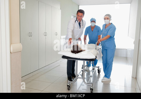 Les médecins de pousser un patient sur une civière à l'hôpital dans un couloir de l'hôpital Banque D'Images