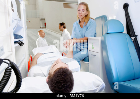 Infirmière un consolateur patient lying on gurney Banque D'Images