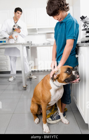 Garçon de caresser un chien avec un vétérinaire dans l'arrière-plan Banque D'Images