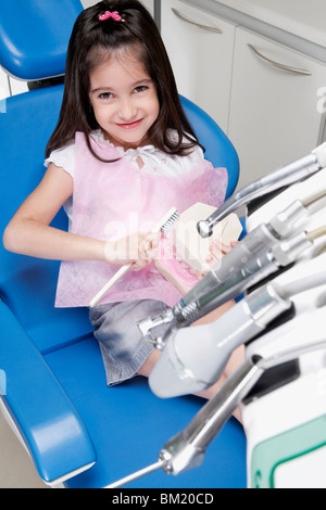 Portrait d'une fille avec une brosse à dents sur les prothèses dentaires dans un cabinet de dentiste Banque D'Images