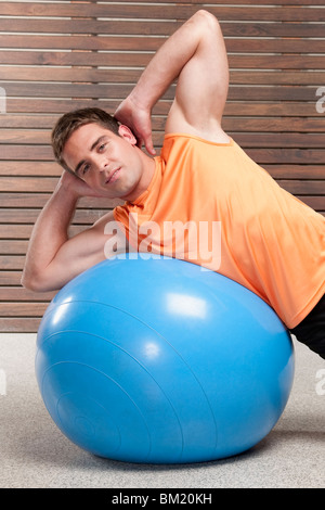 Man exercising on fitness ball un dans une salle de sport Banque D'Images