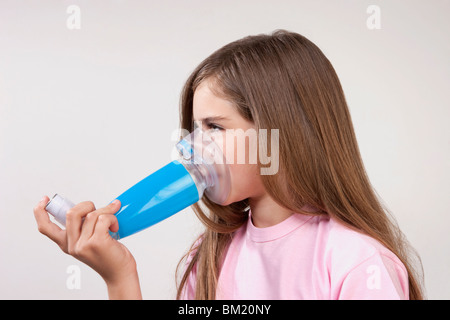 Fille à l'aide d'un inhalateur d'asthme relié par une entretoise Banque D'Images