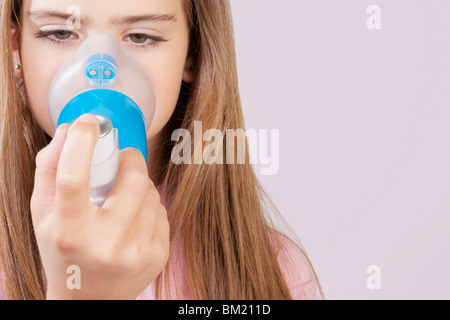 Fille à l'aide d'un inhalateur d'asthme relié avec l'entretoise Banque D'Images