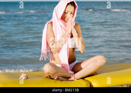 Femme méditant au bord de la mer Banque D'Images